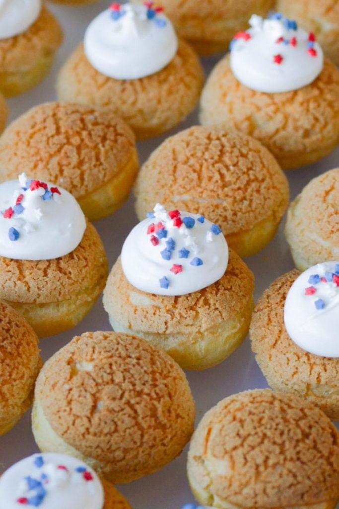 baked cream puffs with craquelin, topped with frosting and sprinkles