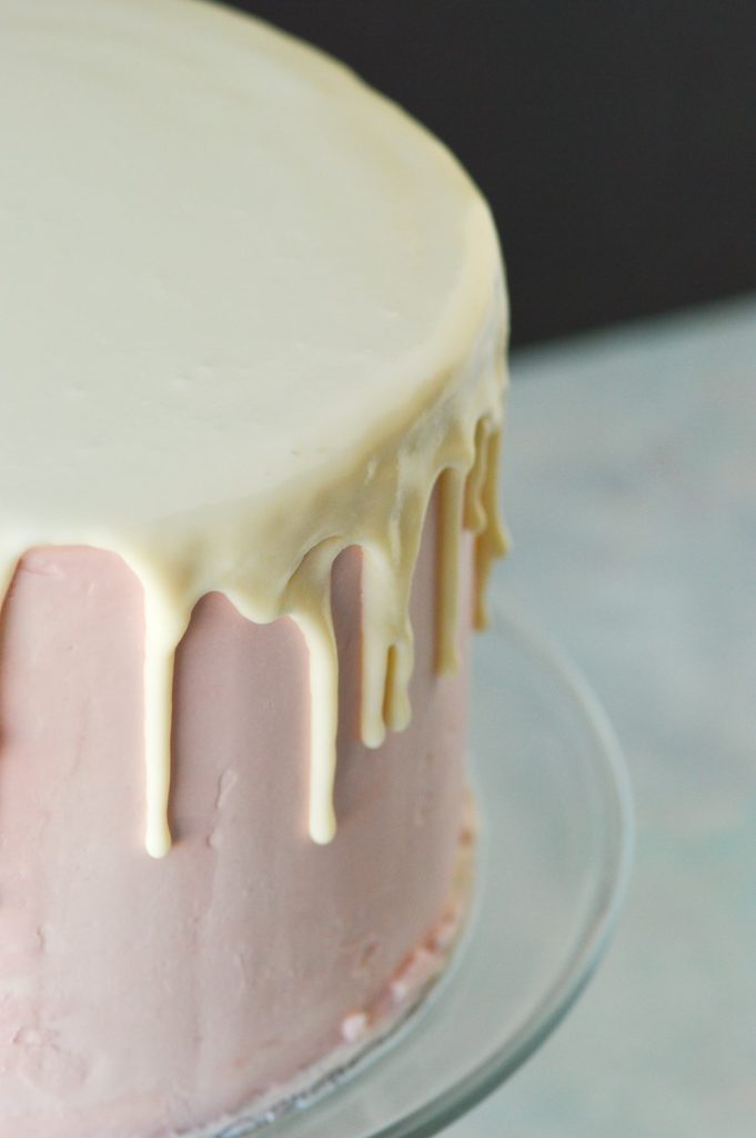 white chocolate ganache drip cake on pink buttercream frosting cake