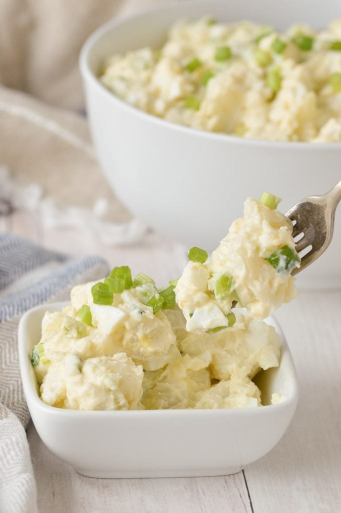 potato salad in dish with fork and tea towel.