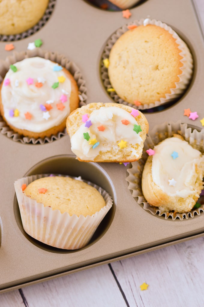 yellow cupcakes with frosting and sprinkles in cupcake holder