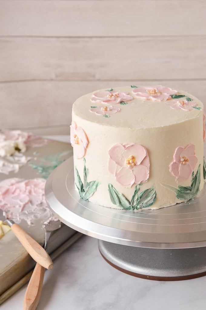 pink flowers painted in buttercream on cake on turntable