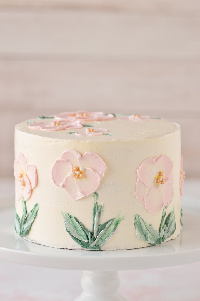 pink flowers painted in buttercream on cake up close on white cake stand