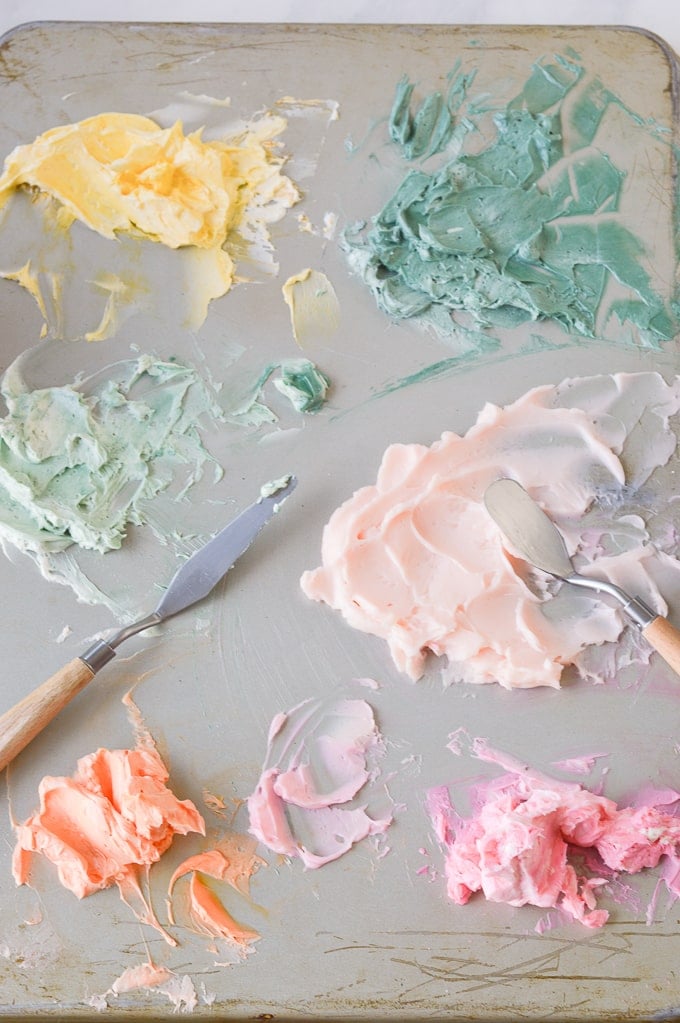 buttercream frosting mixed with palette knife on cookie sheet for cake painting