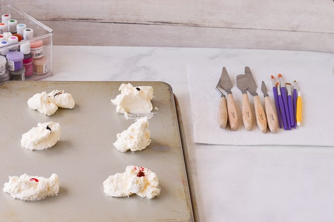 buttercream with food coloring on cake pan with palette knives