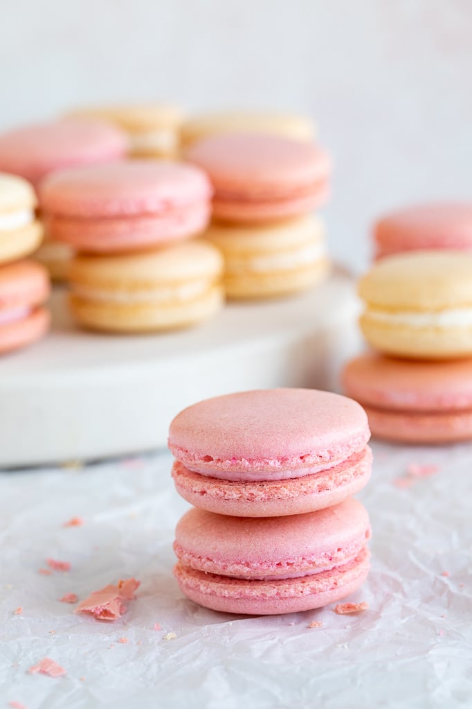 close up of pink macarons with white and pink macarons in background 