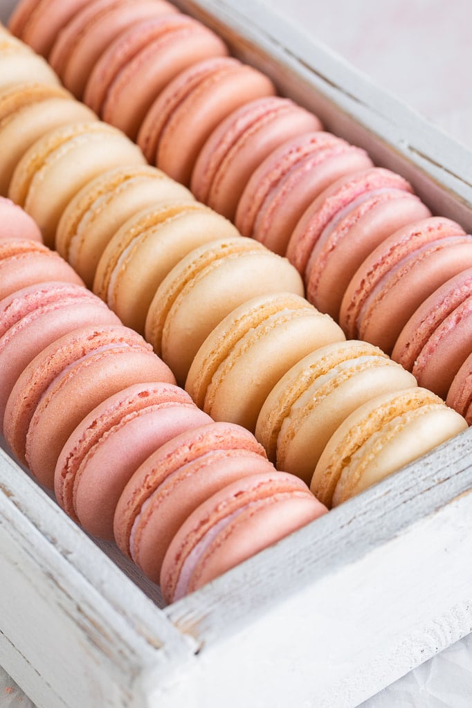pink and white french macarons stacked in box 