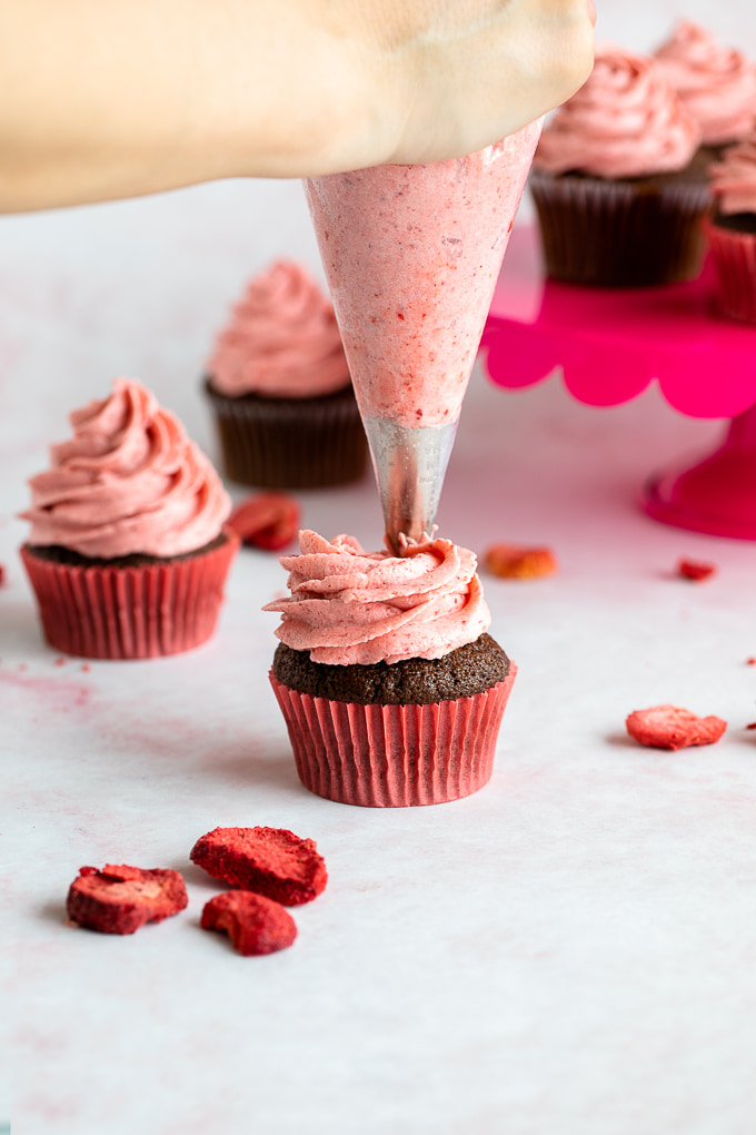 piping strawberry frosting on cupcake 