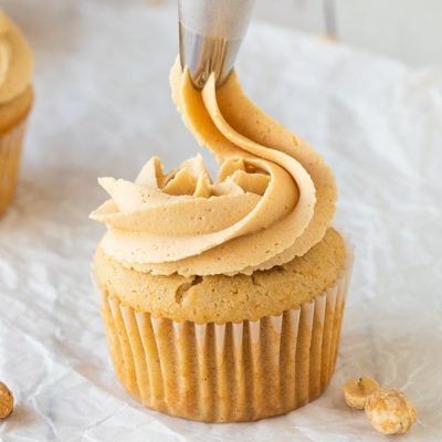 close up of piping peanut butter frosting on cupcake