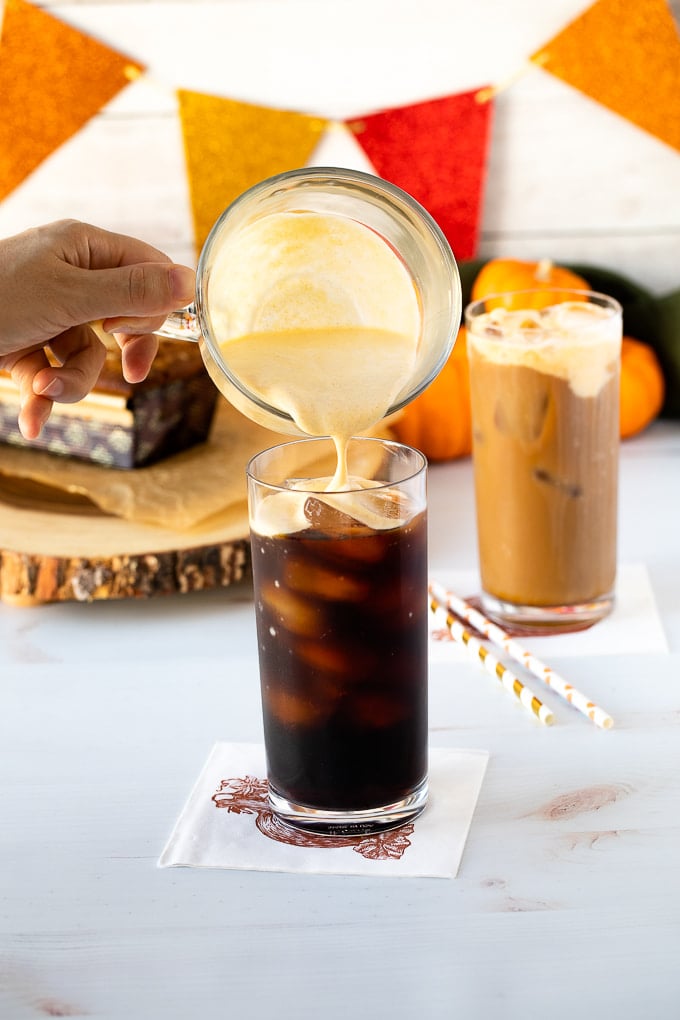 pumpkin cream being poured into cold brew