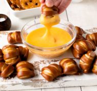 pretzel cheese dip with pretzel being dipped in sauce