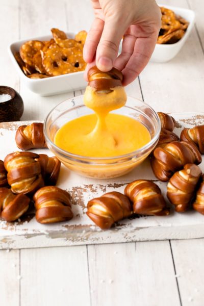 pretzel cheese dip with pretzel being dipped in sauce.
