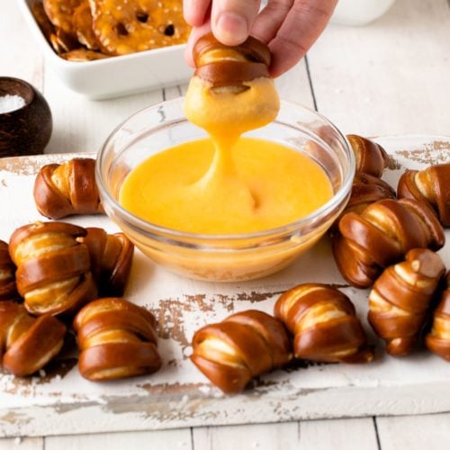 pretzel cheese dip with pretzel being dipped in sauce.