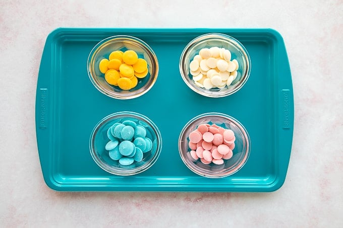 brightly colored candy melts in bowls on baking tray