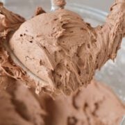chocolate buttercream on standing mixer beater attached to mixer above the bowl.