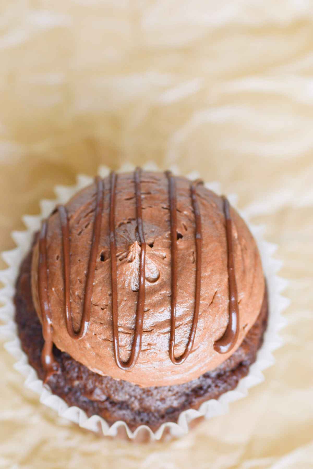 chocolate buttercream frosting on a chocolate cupcake with a chocolate ganache drizzle.