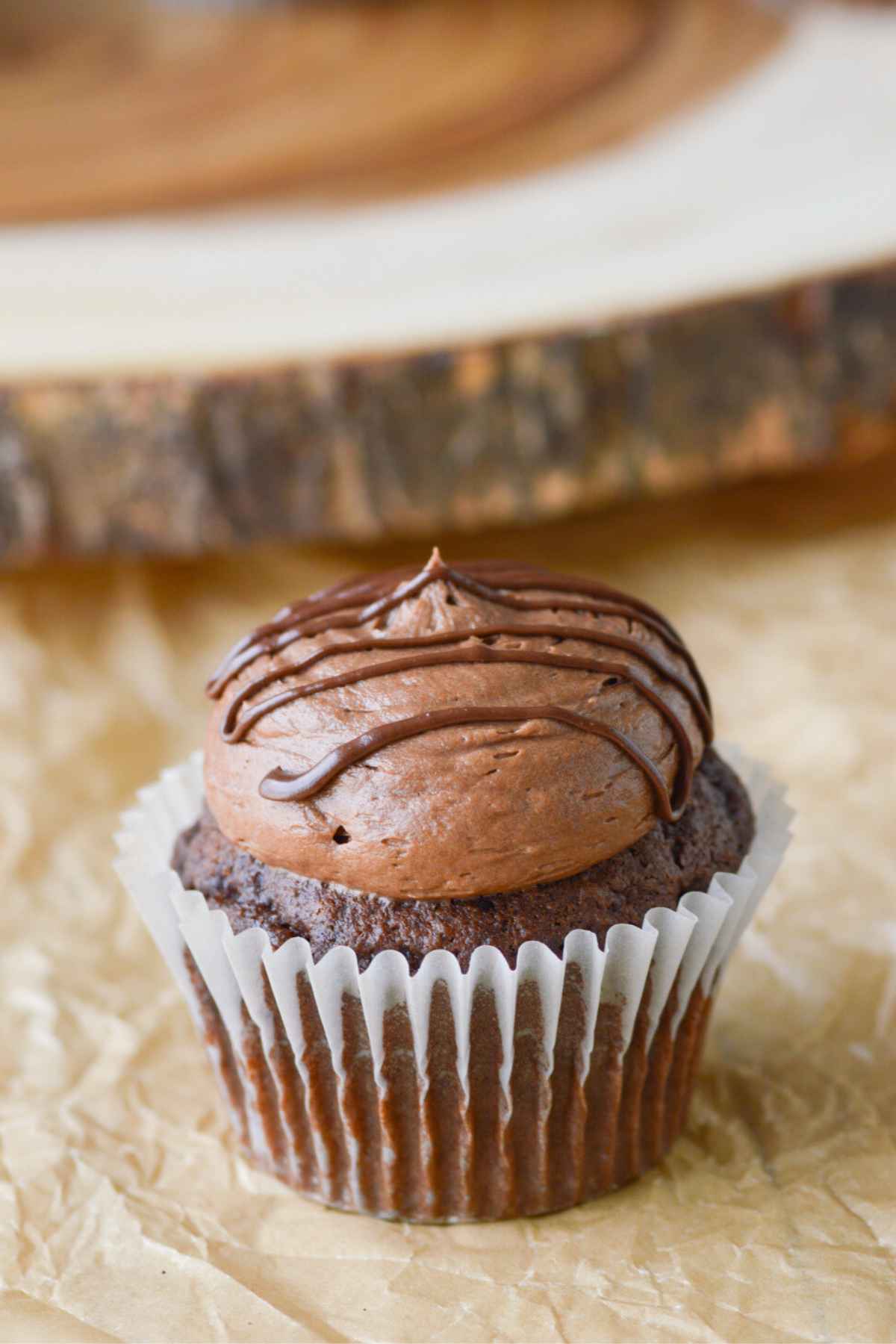 chocolate buttercream frosting on a chocolate cupcake on brown parchment.