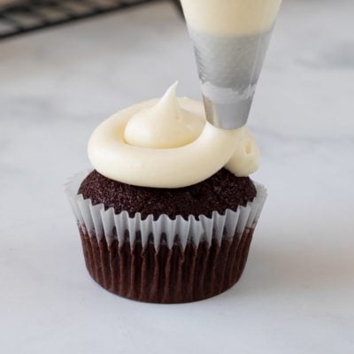 Cream Cheese Frosting being piped on cupcake