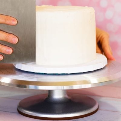 frosting a cake with a bench scraper