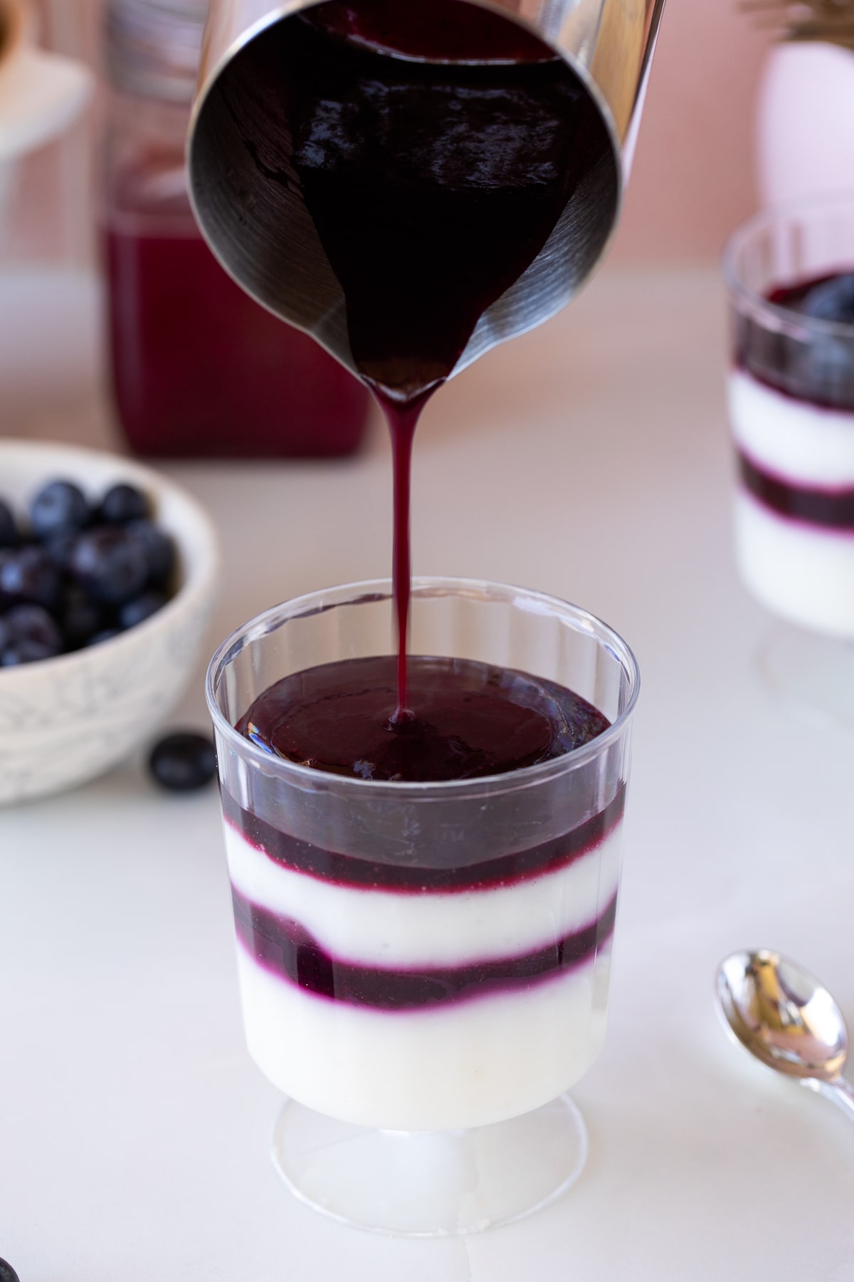 pouring blueberry coulis over panna cotta.