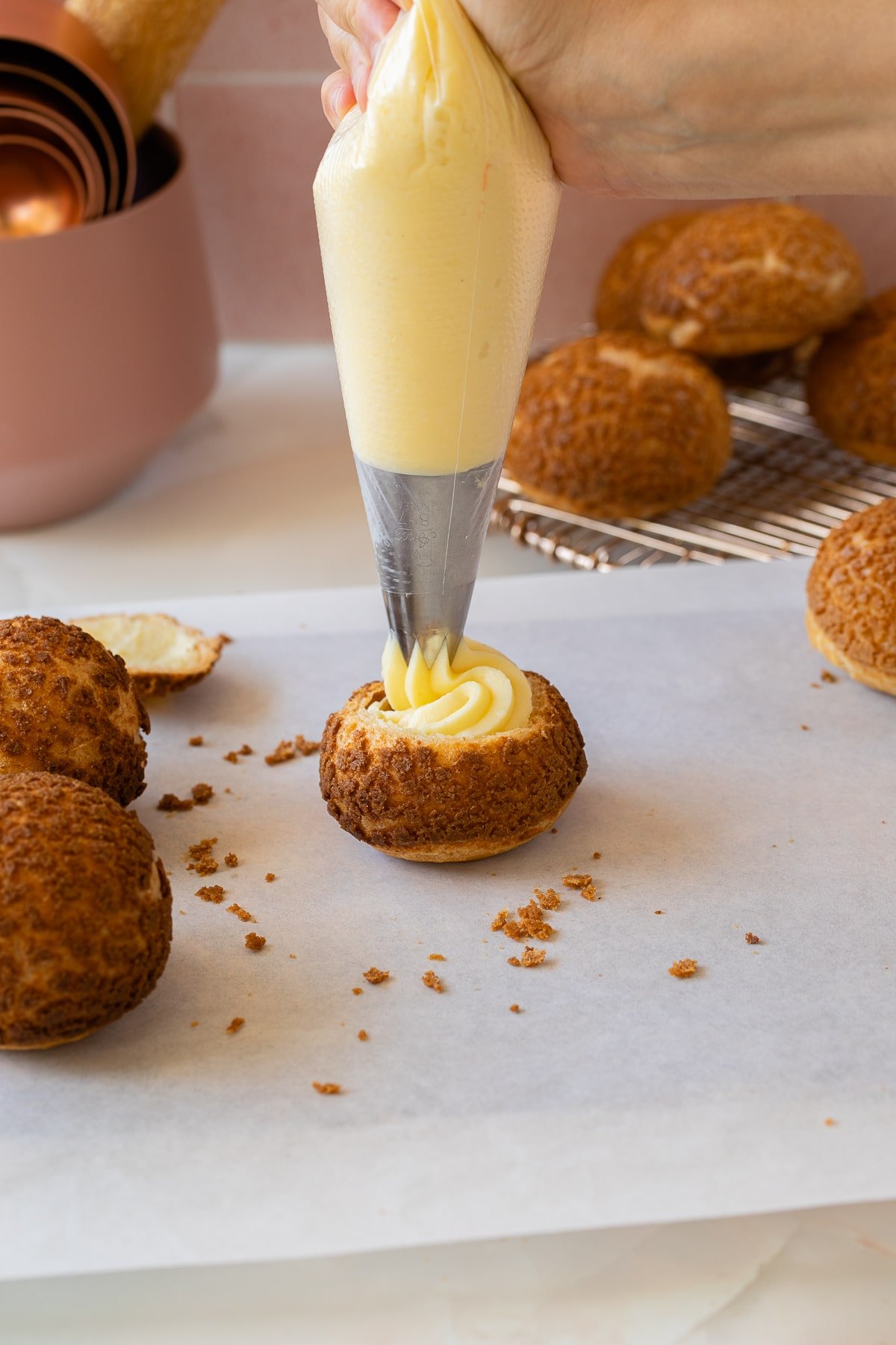piping baked choux au craquelin with pastry cream.