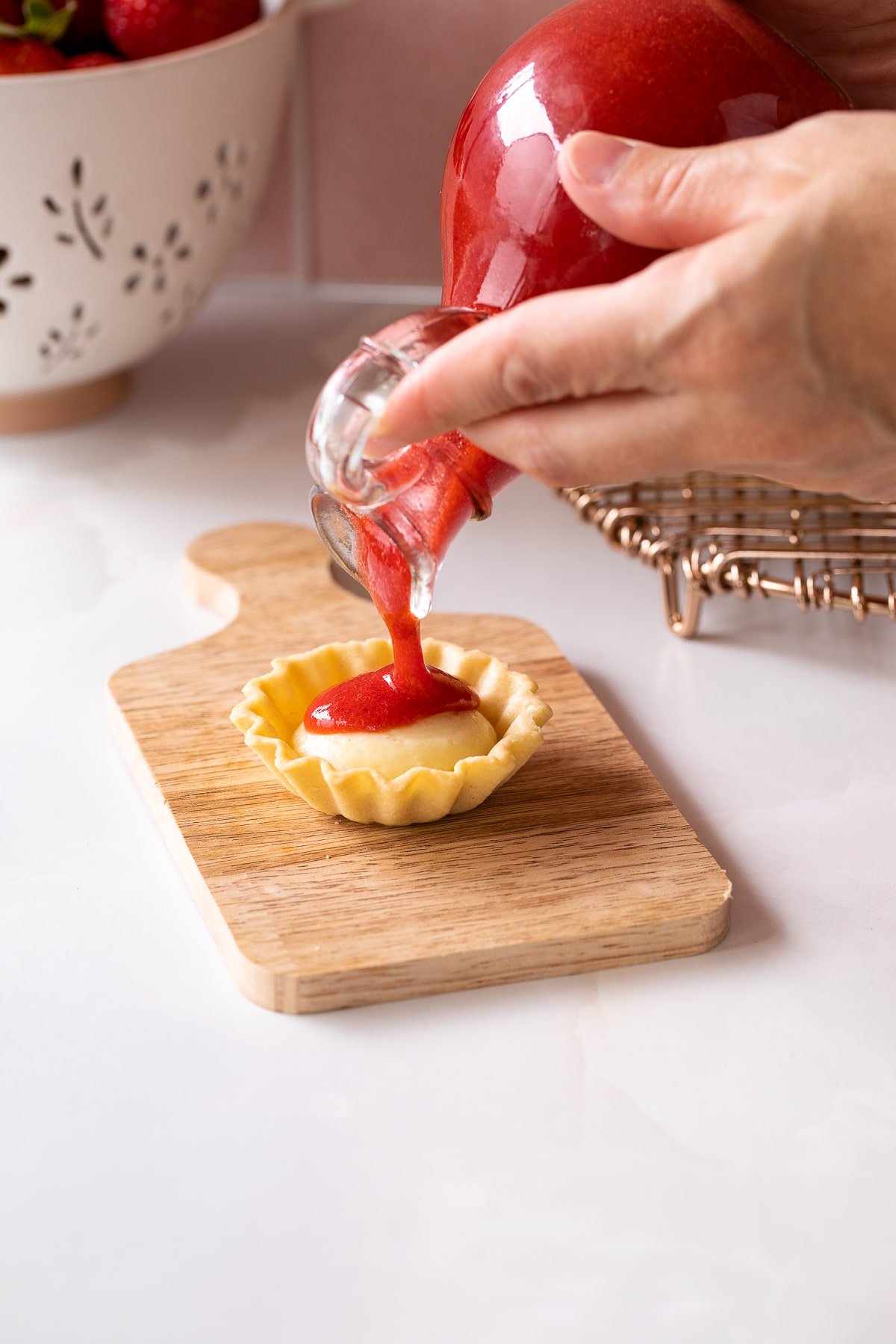 pouring strawberry coulis on tart.