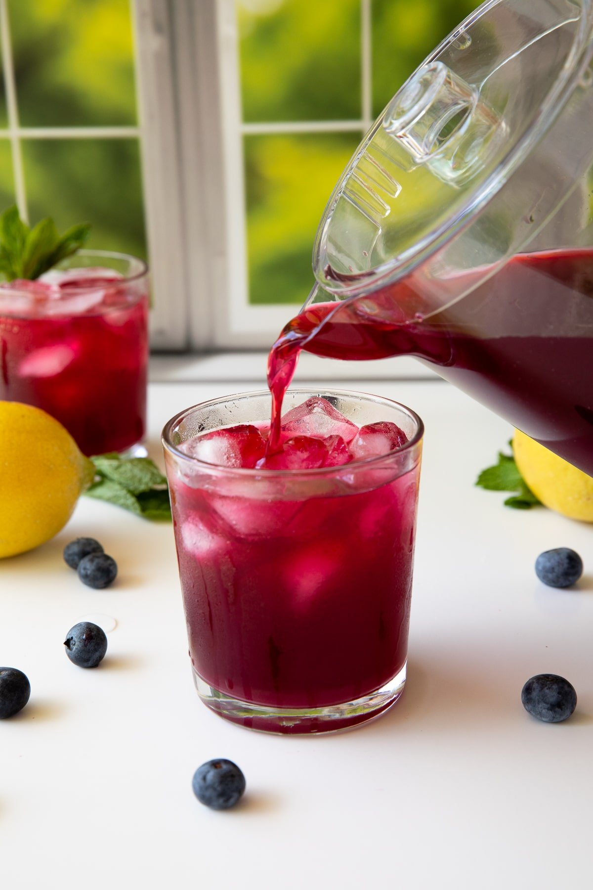 pouring blueberry lemonade into a glass.