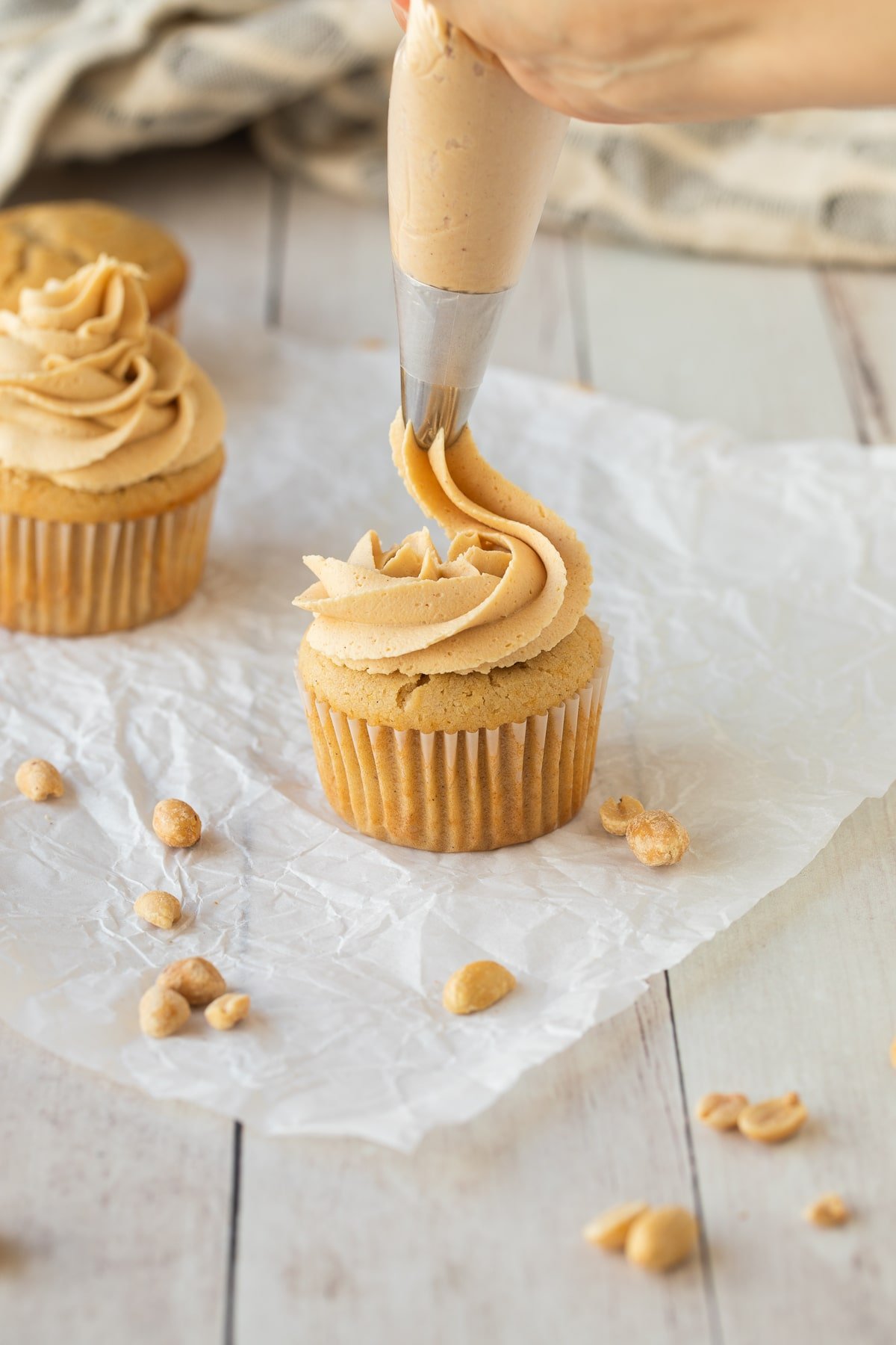 piping peanut butter frosting on cupcake.