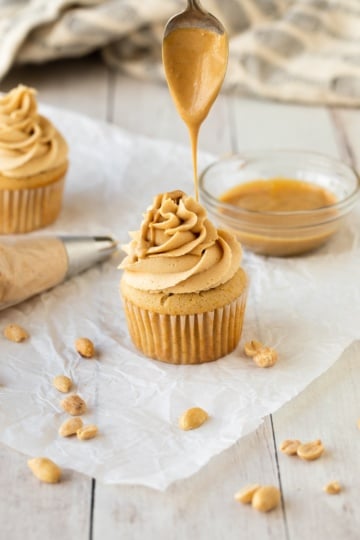 peanut butter frosting on cupcake dripping melted peanut butter with spoon.