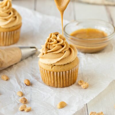 peanut butter frosting on cupcake dripping melted peanut butter with spoon.