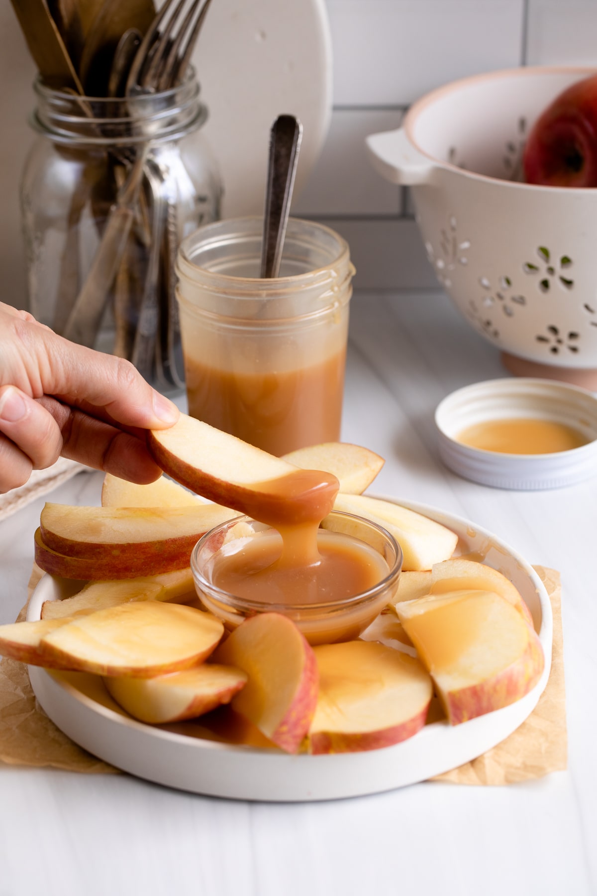 apple being dipping into caramel sauce.