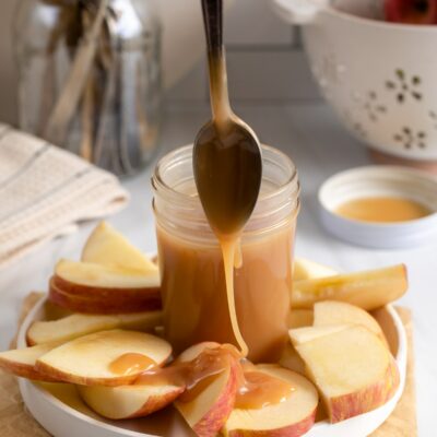 caramel sauce being dripped on apples.