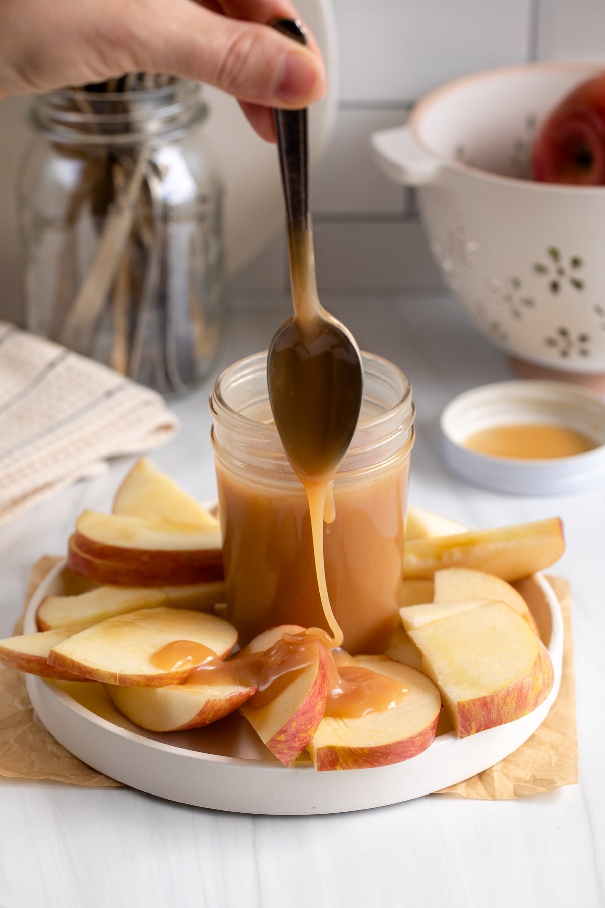 caramel sauce being dripped on apples.