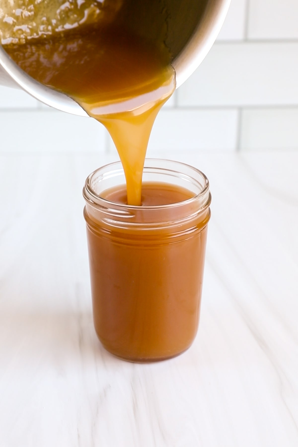 caramel sauce pouring into jar.