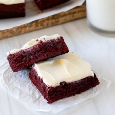 two red velvet brownies on parchment up close with milk.
