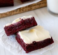 two red velvet brownies on parchment up close with milk.