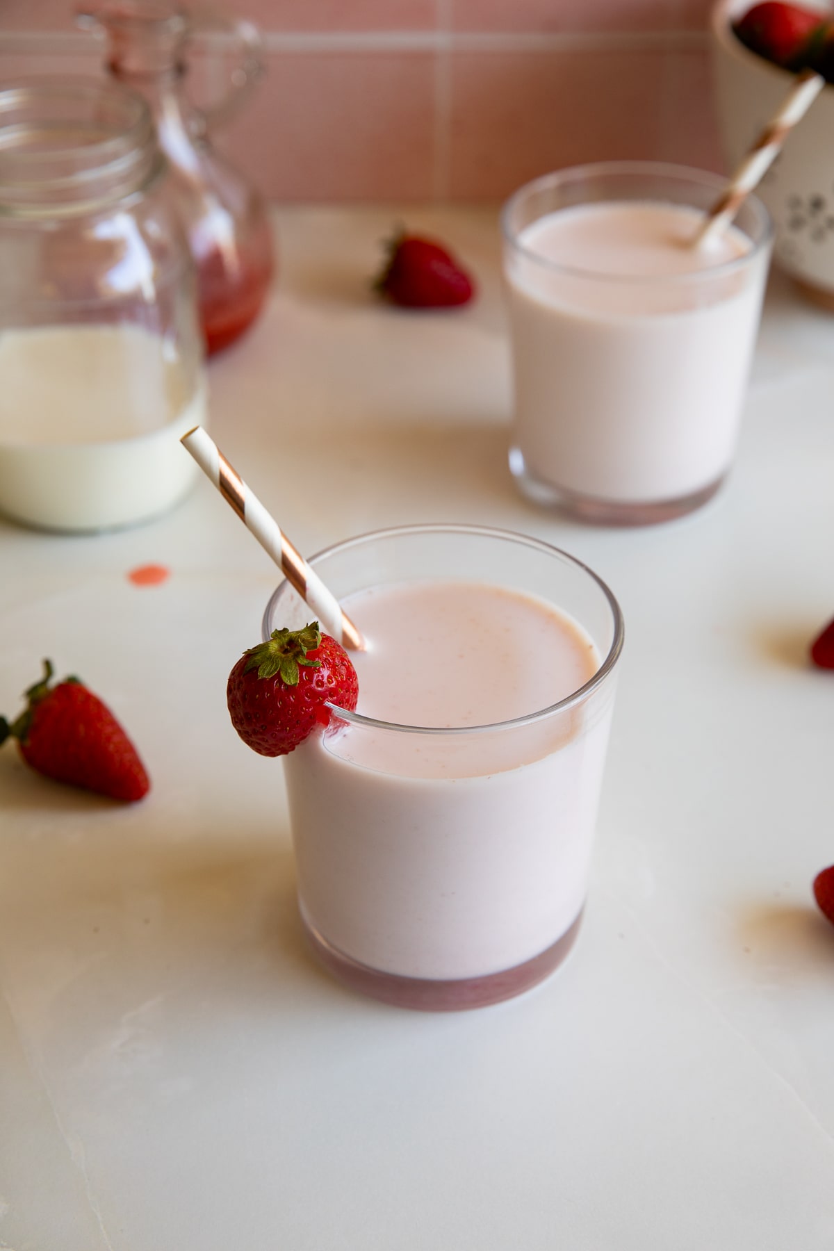 strawberry milk in glass with strawberries and straw.