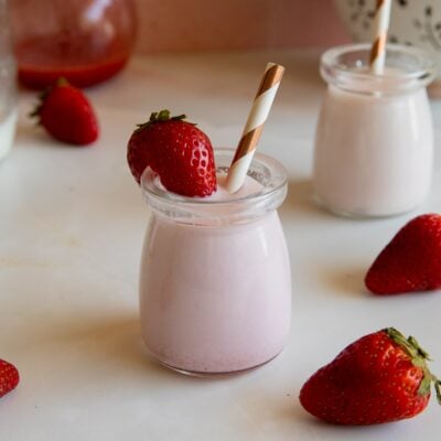 strawberry milk in jar with strawberry and straw.