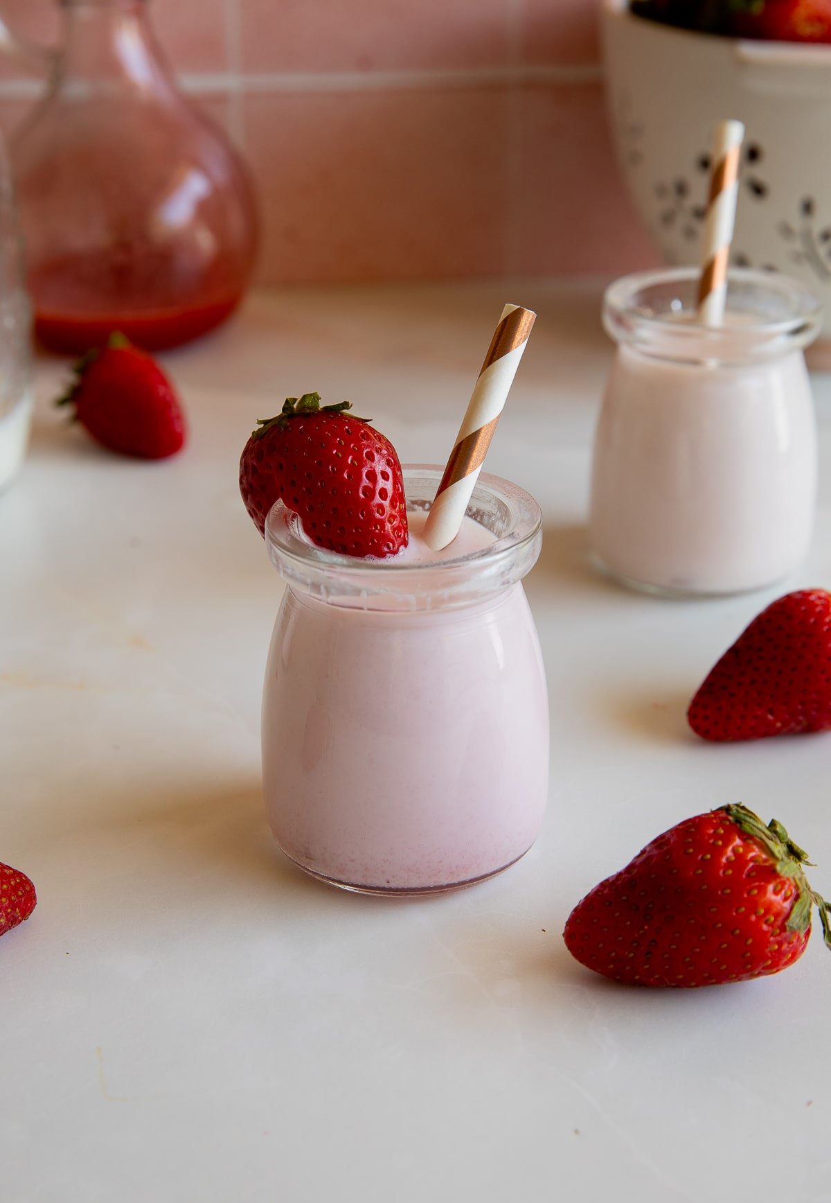 strawberry milk in jar with strawberry and straw.