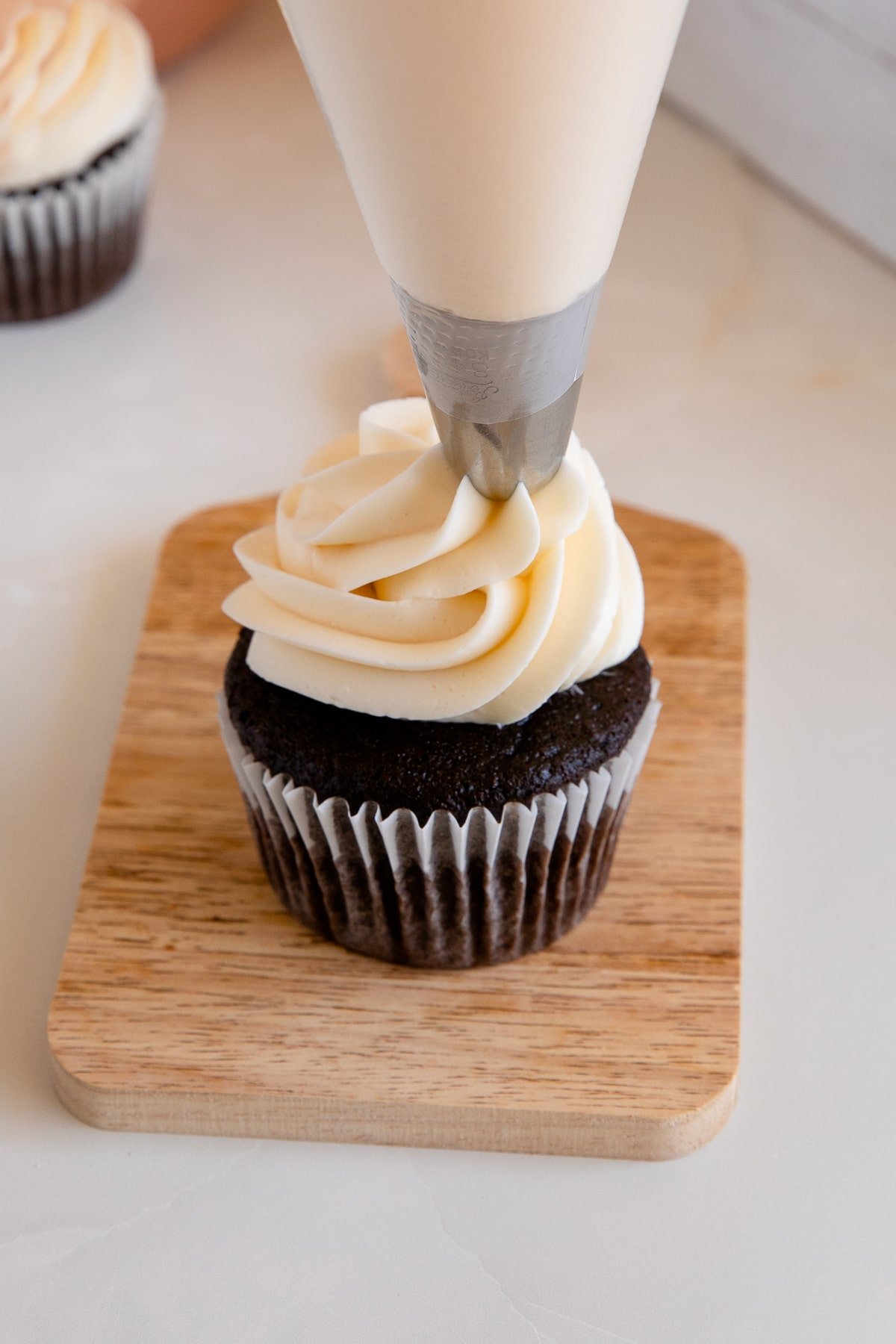 piping Swiss meringue buttercream on cupcake.