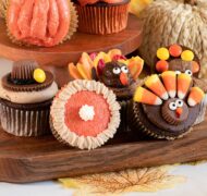 decorated thanksgiving cupcakes on wooden tray.