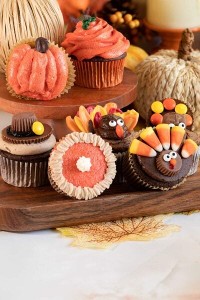 decorated thanksgiving cupcakes on wooden tray.