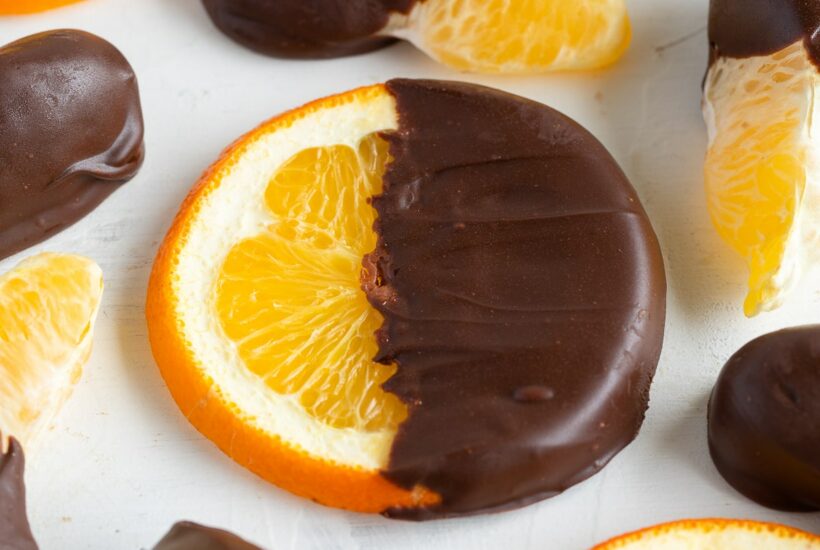 chocolate covered orange slices on cutting board.