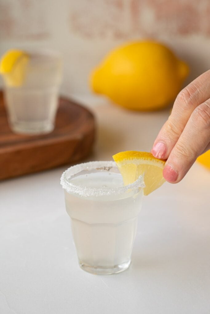 adding lemon wedge garnish to lemon drop shot.