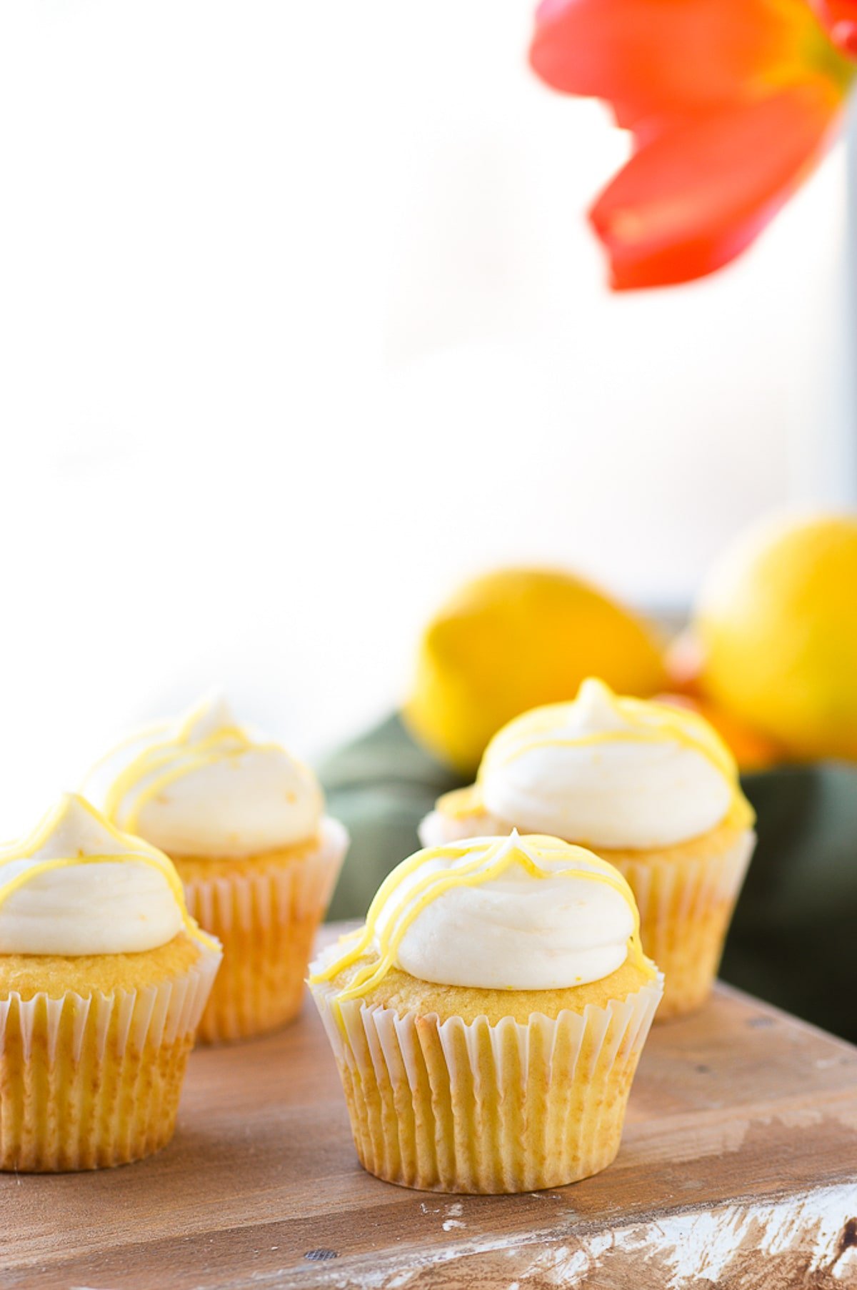 lemon buttercream frosting on cupcakes on wood serving platter.