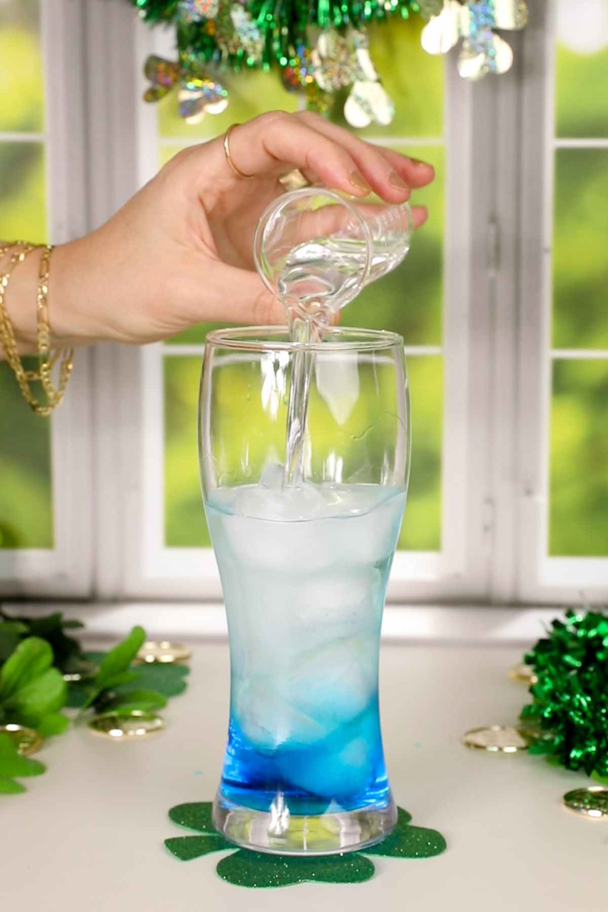 pouring liquor into a glass with ice for a Irish trash can drink.