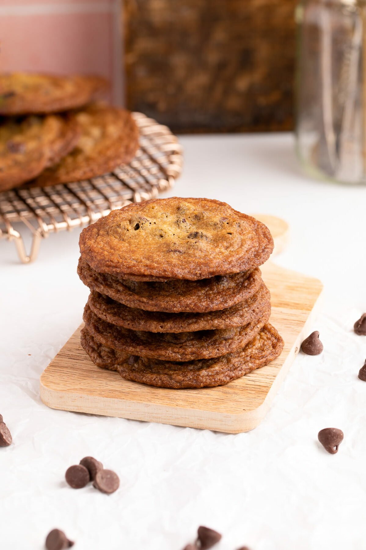 crispy chocolate chip cookies stacked on serving board.