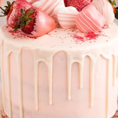 pink champagne cake with chocolate drip and strawberries up close.