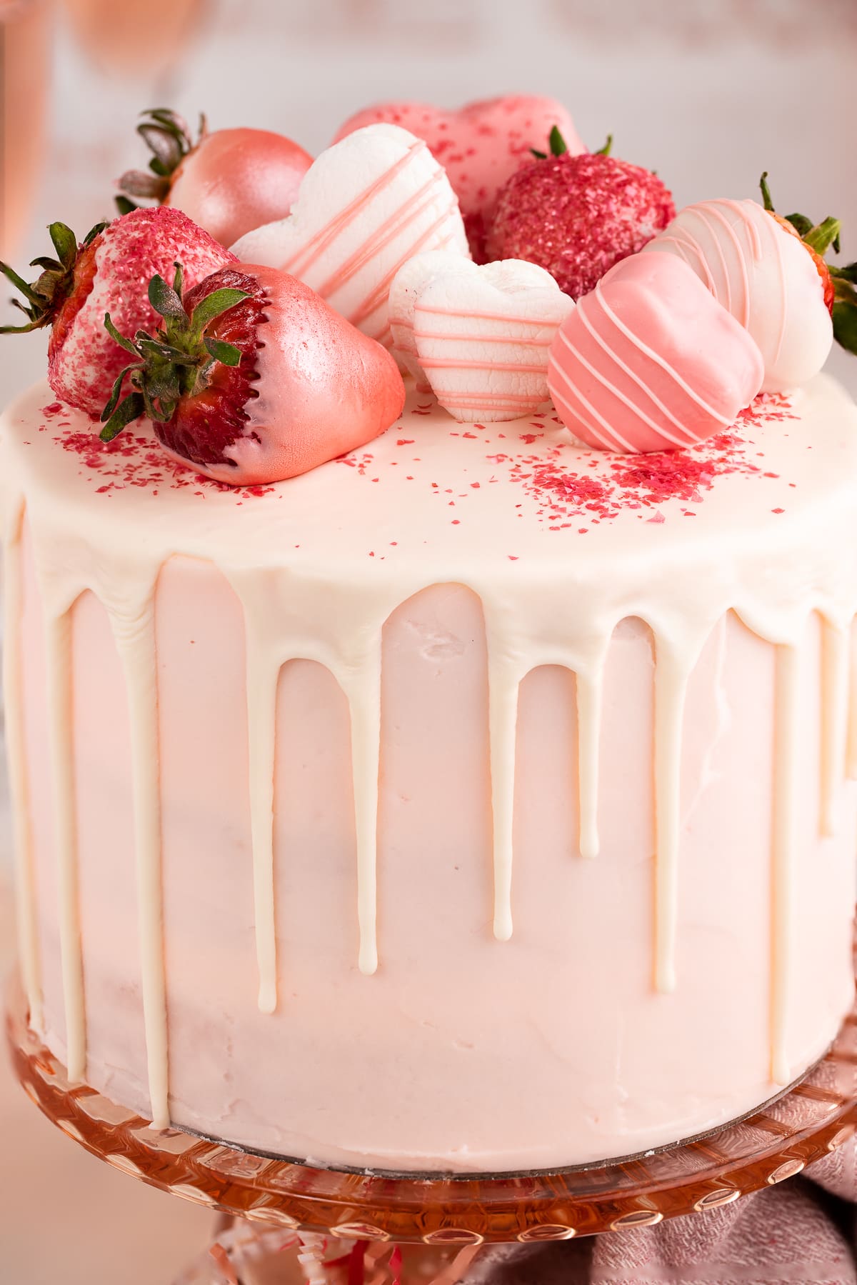 pink champagne cake with chocolate drip and strawberries up close.
