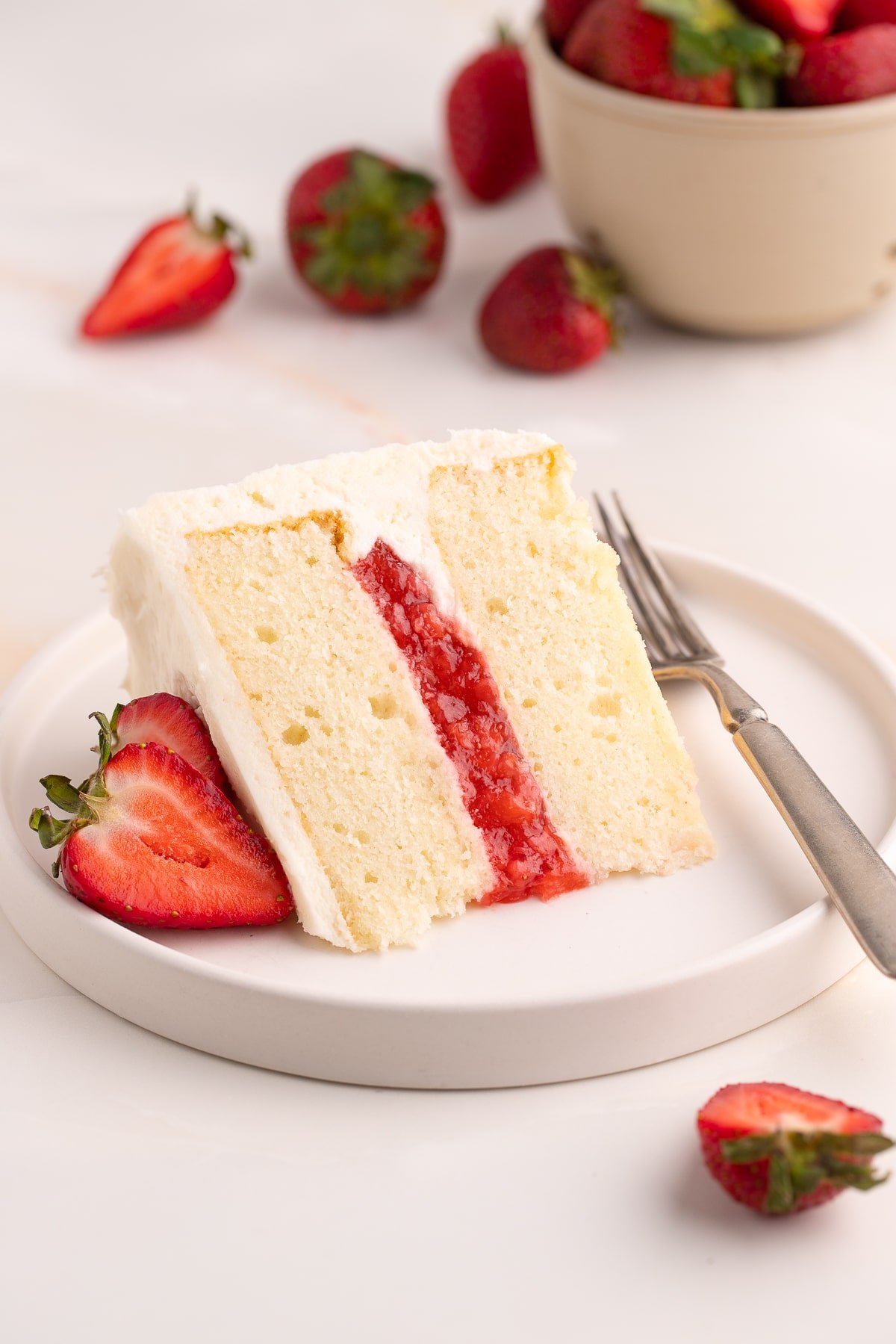 vanilla cake with strawberry filling on plate with forlk/