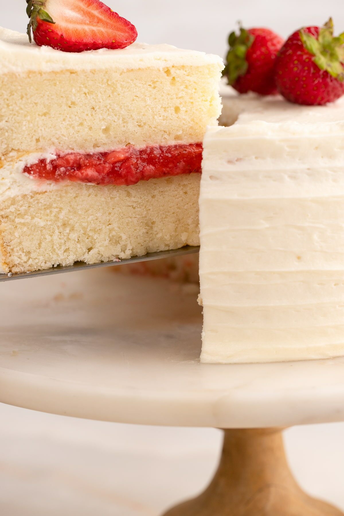 slicing a Vanilla Cake with Strawberry Filling up close.